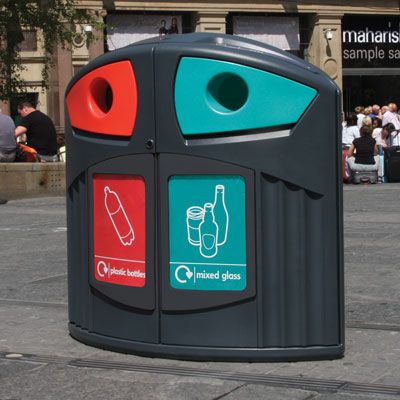 Sopsorteringskärl för plastflaskor och glas i stadsmiljö, grå, röd, turkos.